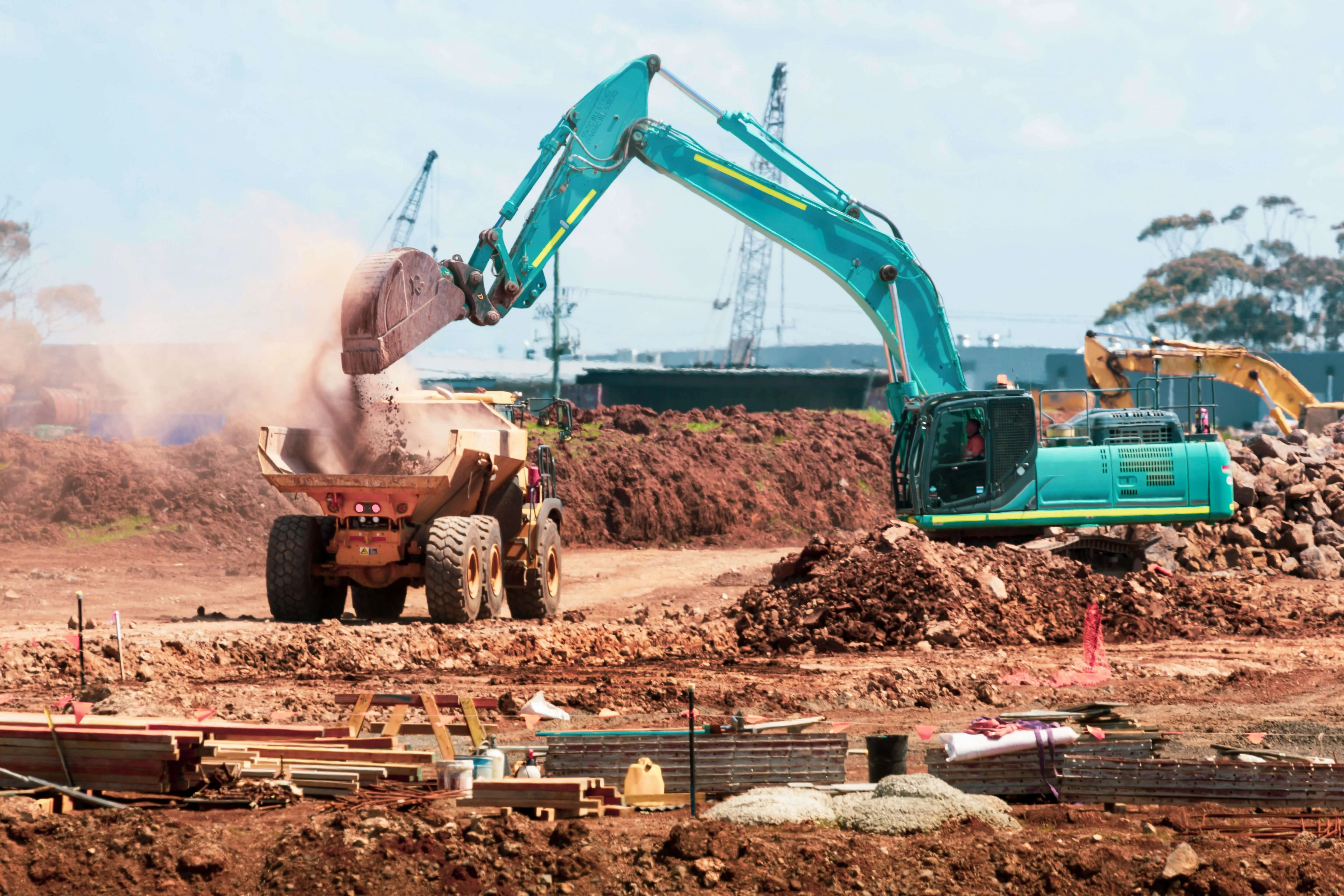 Excavator loading gravel and soil onto a sino truck
